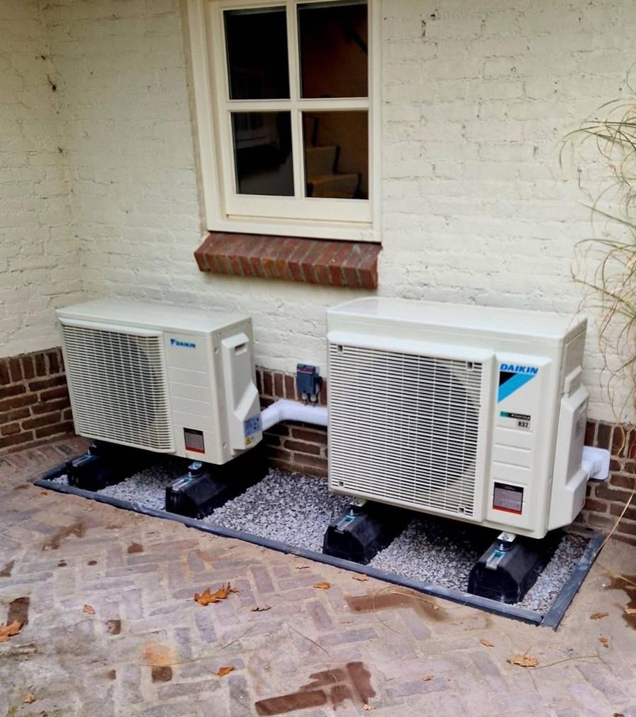Twee Daikin warmtepomp-buitendelen op voeten in een grindbak naast een woning